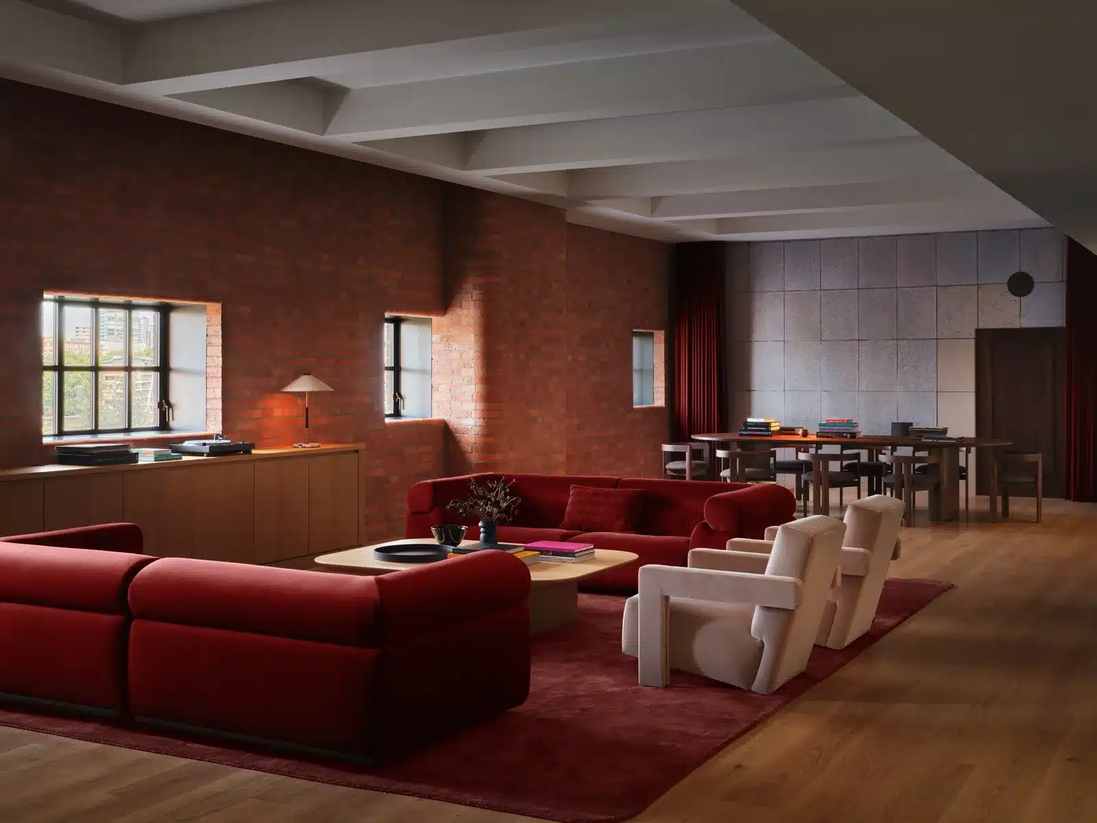 Lounge with brick walls, red sofas and a dining table inside Apple Music Radio’s London studios