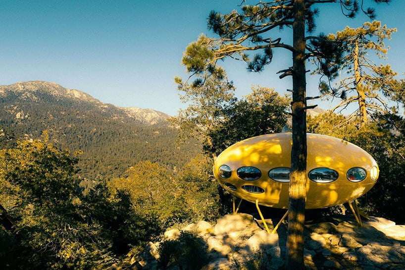 Yellow Futuro house among pine trees with the San Jacinto Mountains in the background
