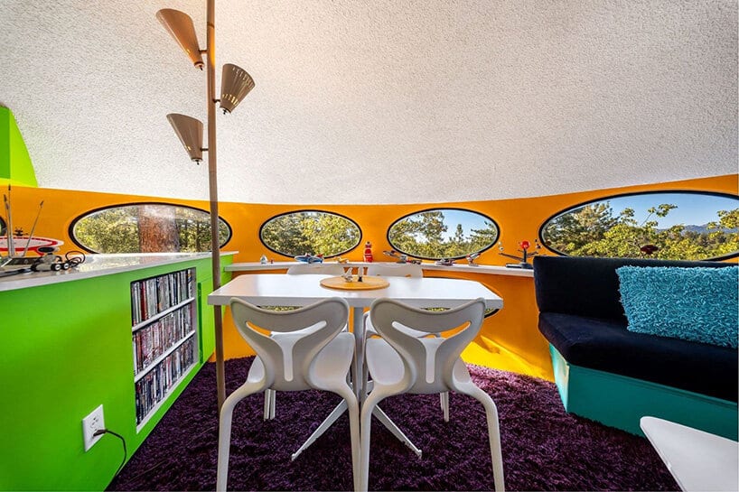 Futuro dining area with white table and chairs, green cabinetry and teal sofa