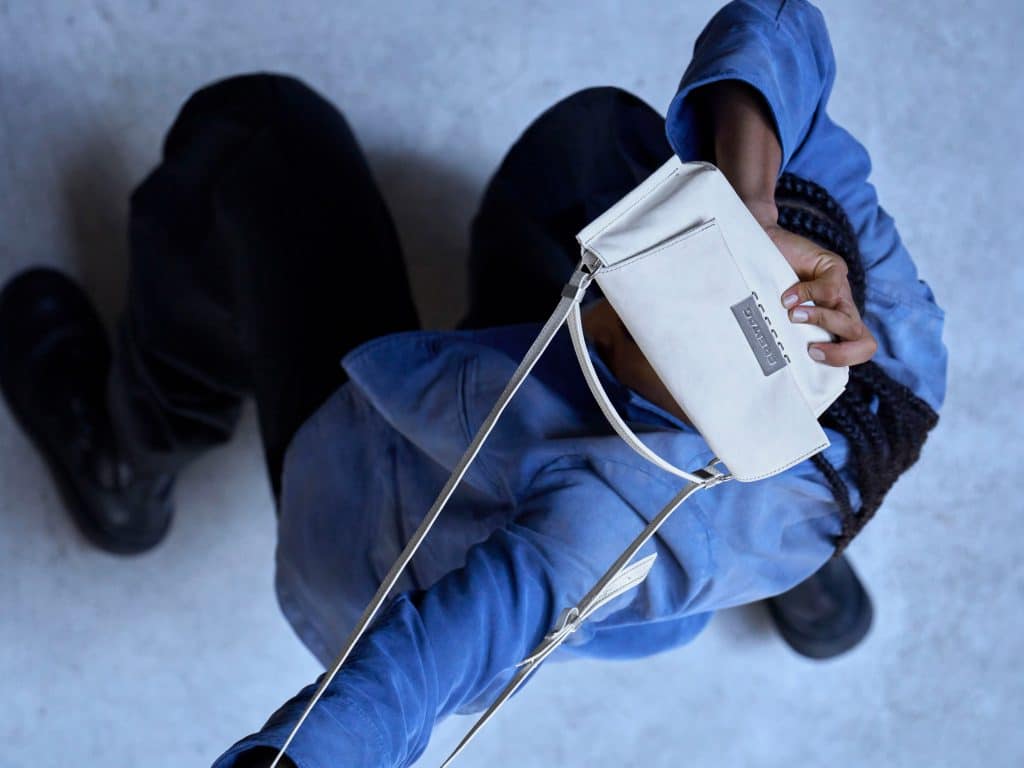 Person holding a white Freitag Reference crossbody bag in front of their face