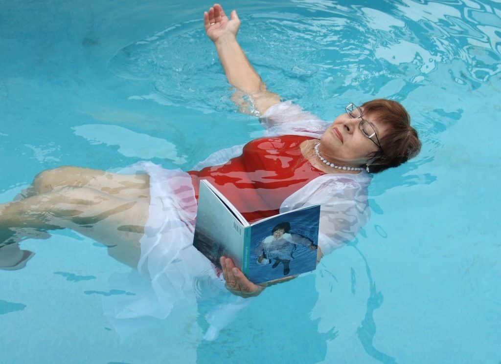 Woman floating in a swimming pool holding a book, from Erik Kessels’ In Almost Every Picture