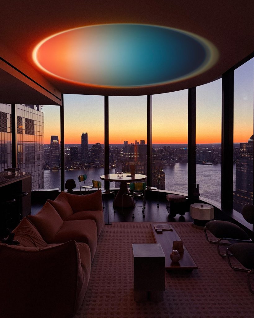 Living room with large windows and a city view, with Halo Horizon projecting a sunset gradient on the ceiling