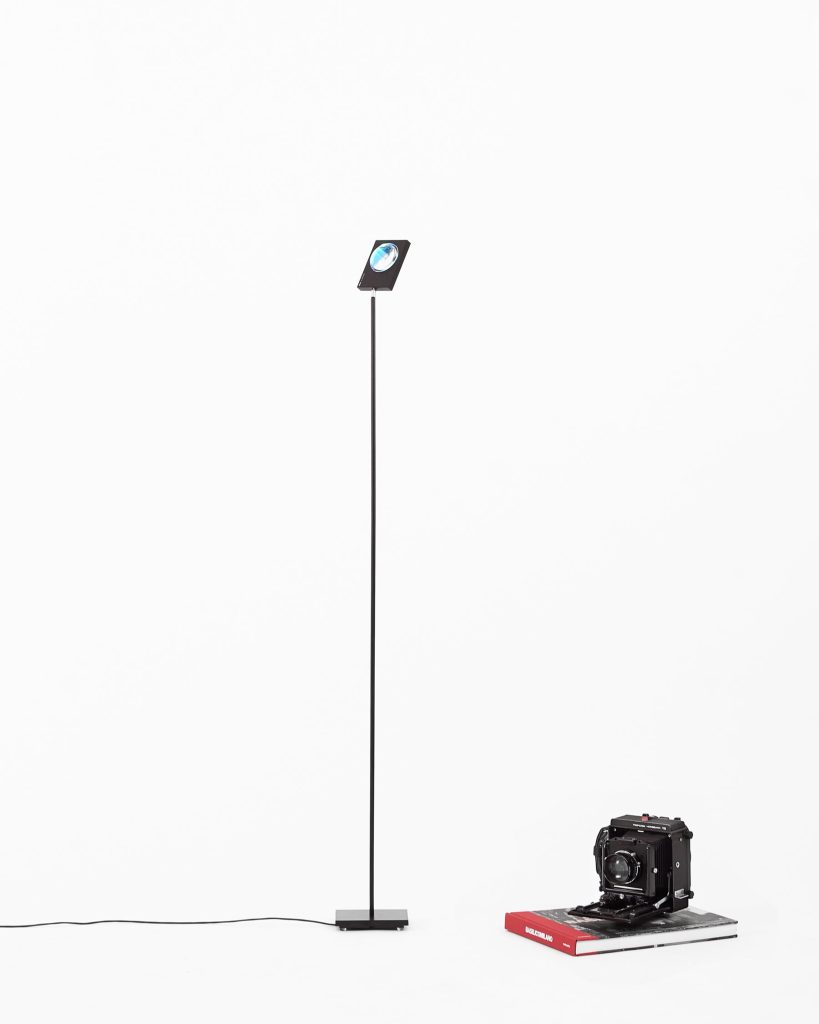 Halo Horizon floor lamp switched off on a white background next to books