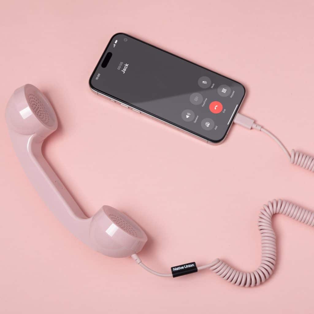 Pink Native Union POP Phone handset connected to a smartphone showing an incoming call on a pink background