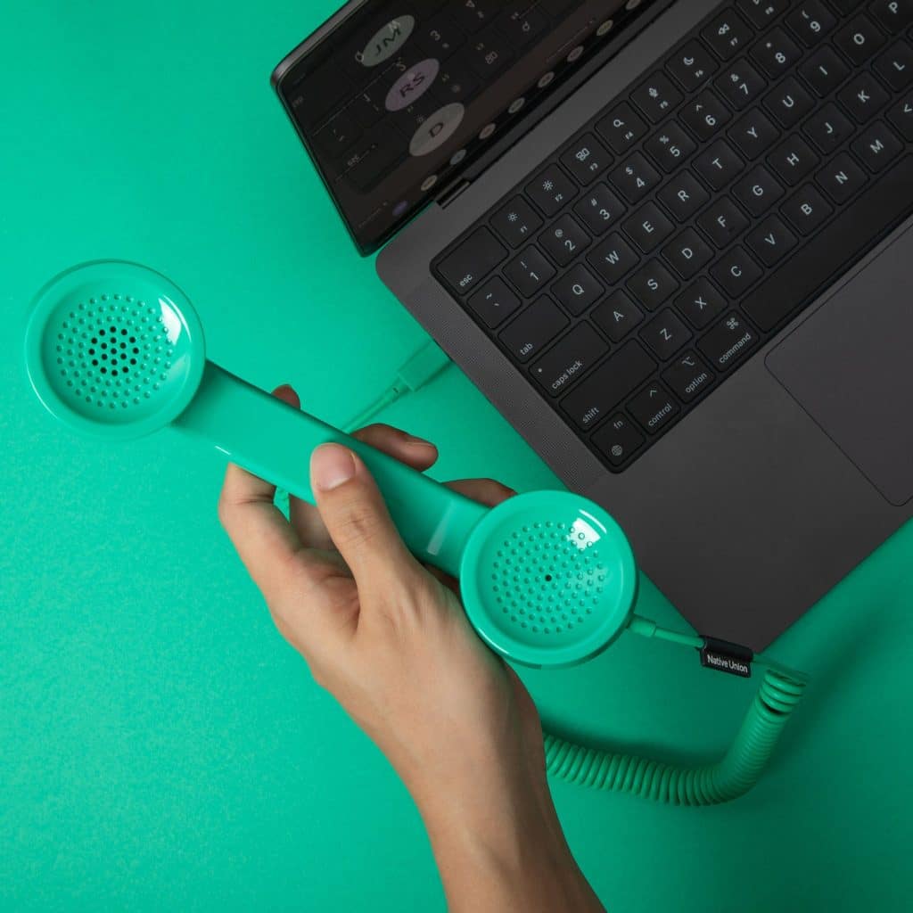 Green Native Union POP Phone handset connected to a laptop on a green background