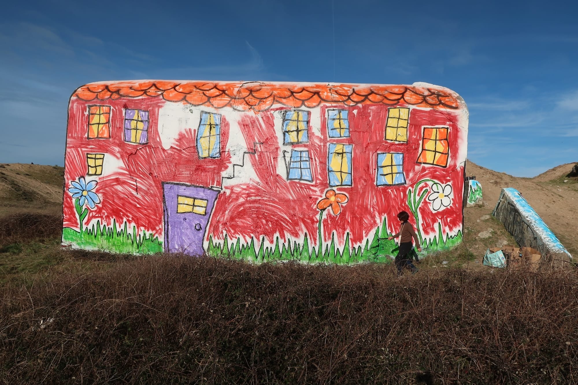 A World War II bunker on the Atlantic Wall painted by The Wa to look like a child's drawing of a house