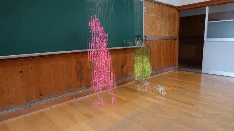 Pink and green bead figures of children in front of the blackboard