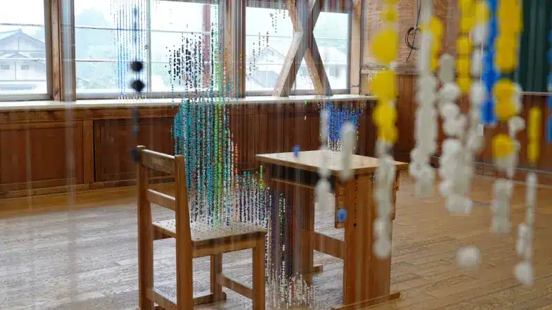 Strings of coloured ironing beads hanging between school desks