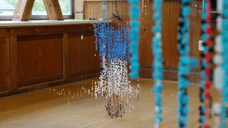 Close-up of the beaded strands, with a child figure in blue and white behind them